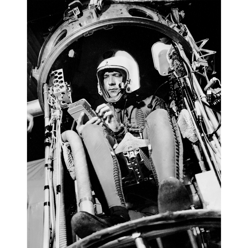 David G. Simons trägt einen Helm und sitzt in einer technischen Kapsel im Jahr 1957