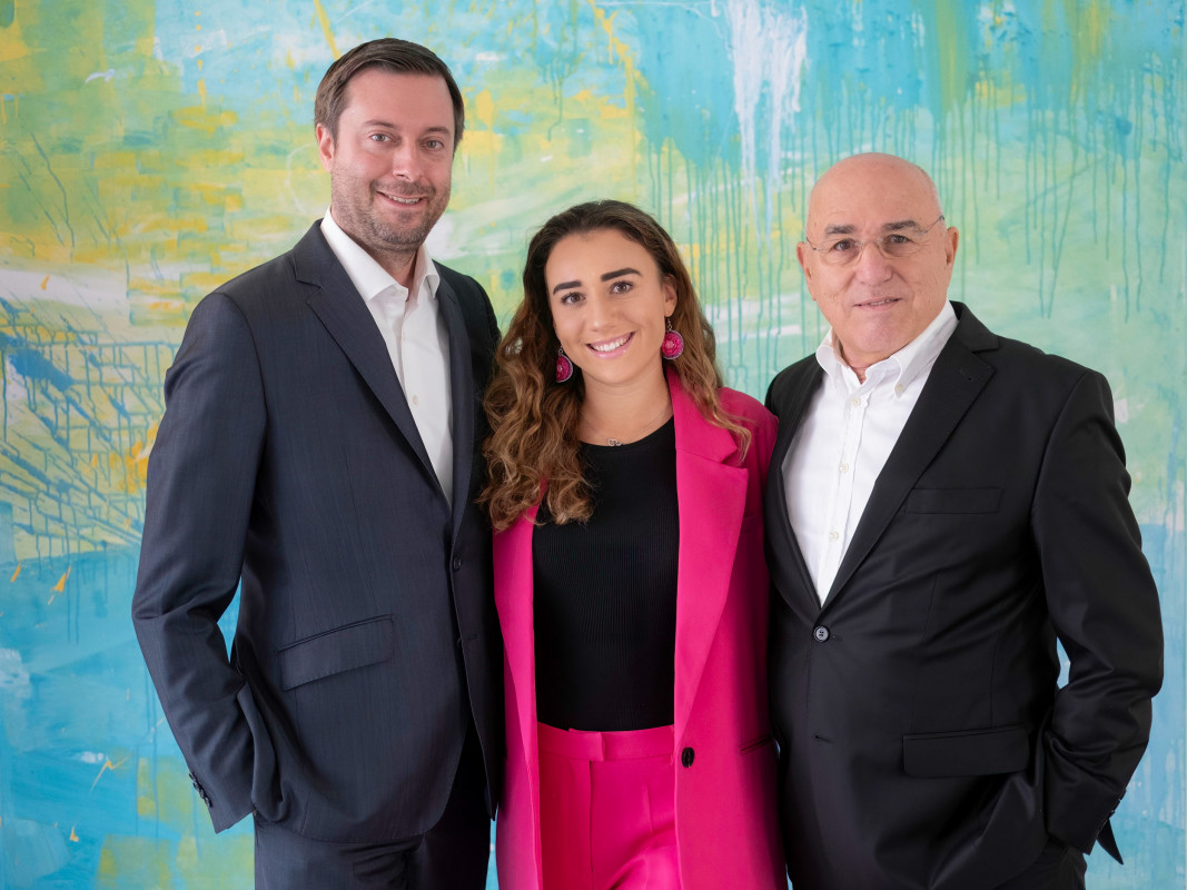 Von links nach rechts Benjamin Asmus, Carina und Andreas Peiker, die Herren in dunklen Anzügen und die Dame in einem pinken, alle freundlich lächelnd